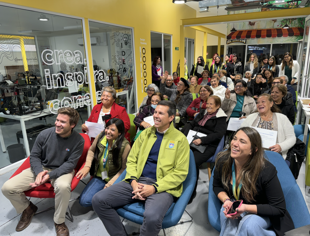 Fotografía grupal de aproximadamente 35 personas que participaron de la sesión de cierre del Programa de Empoderamiento Digital de Conecta Mayor UC. En primer plano alcalde de Renca y la representante de la  empresa Lipigas.