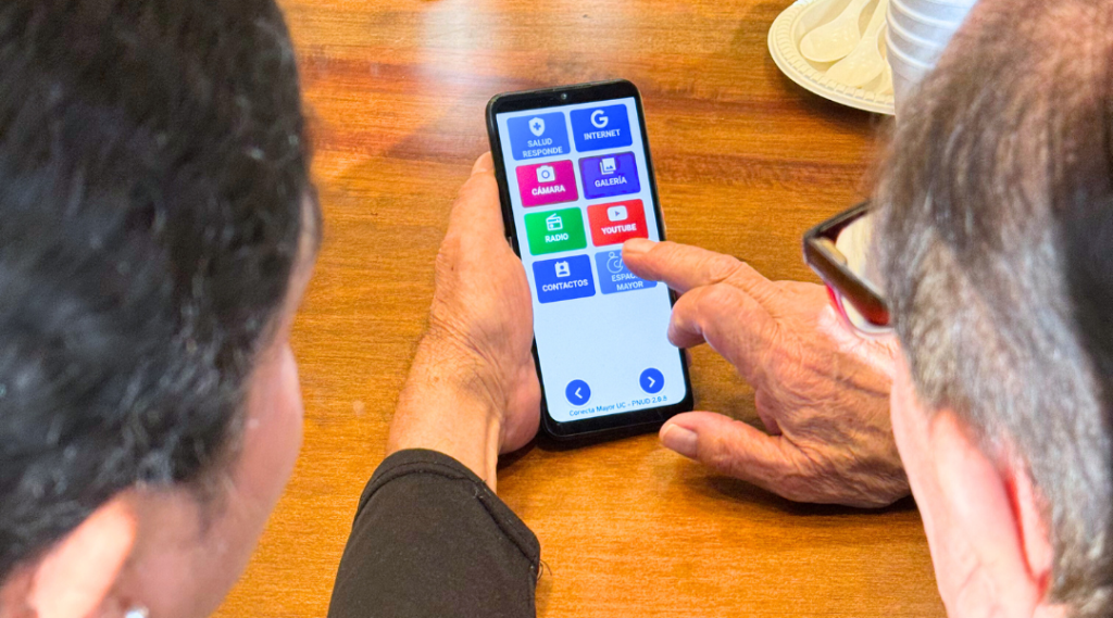 Una embajadora de App Mayor enseña a descargar App Mayor a un hombre mayor.