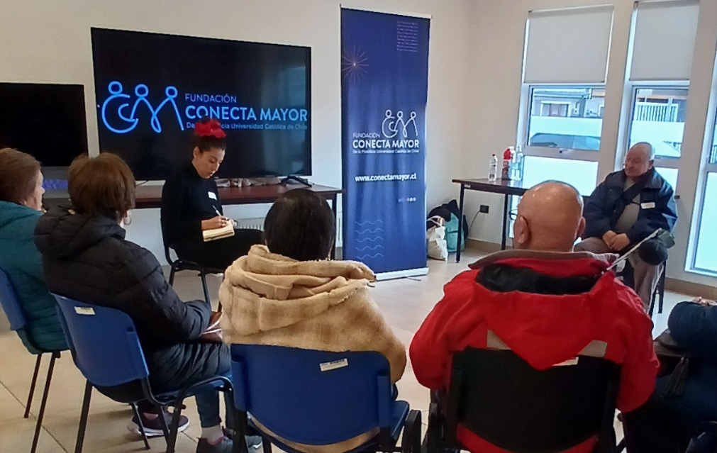 imagen grupal con Bernardita Cuevas del equipo de COnecta Mayor UC junto a personas mayores, todos conversando sentados en círculo.
